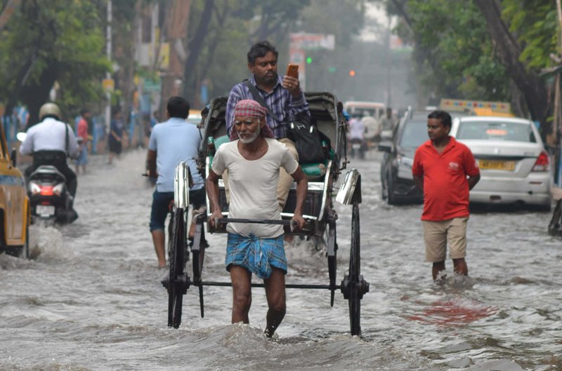 Rickshaw puller wades through water-logged street in Kolkata