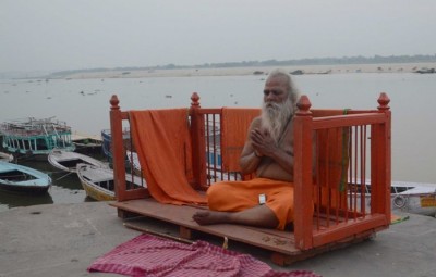 Sadhu meditates on banks of holy river of Ganges in Varanasi 