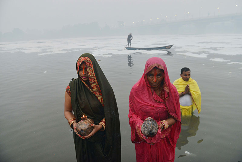 Devotees worship the rising sun at the banks of Yamuna in Delhi