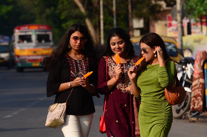 Three girls cherish ice cream on hot summer afternoon in Kolkata